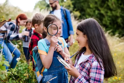 students in nature, looking through a magnifying glass